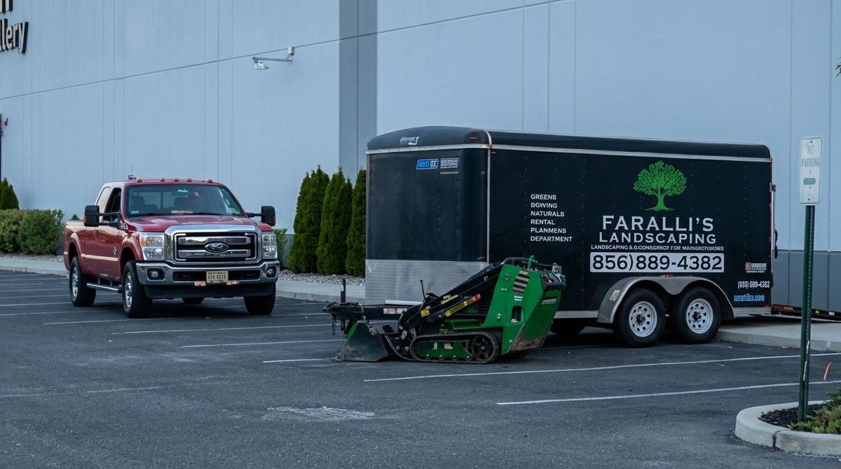 Faralli’s Landscaping branded trailer, red pickup and compact loader on a job site